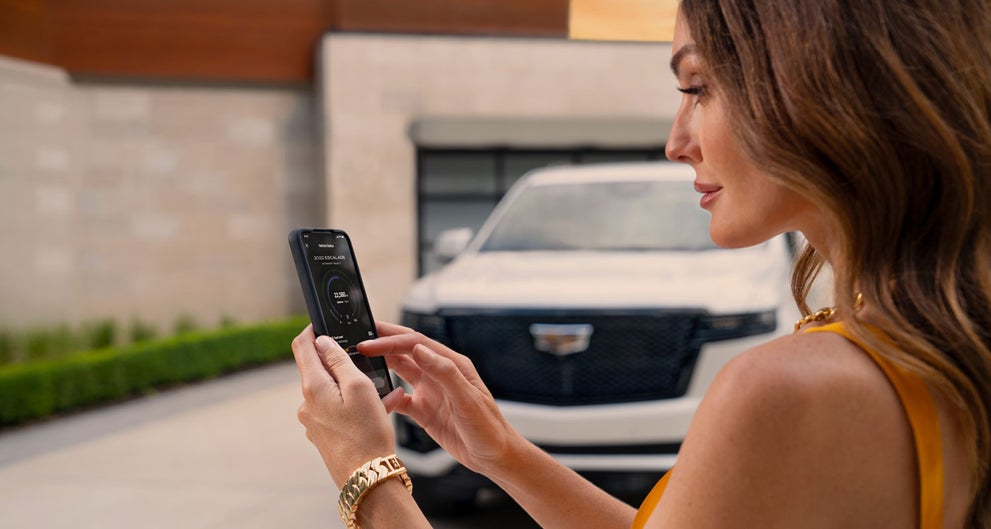 lady checking her mobile with a Cadillac vehicle background | Camargo Cadillac in CINCINNATI OH